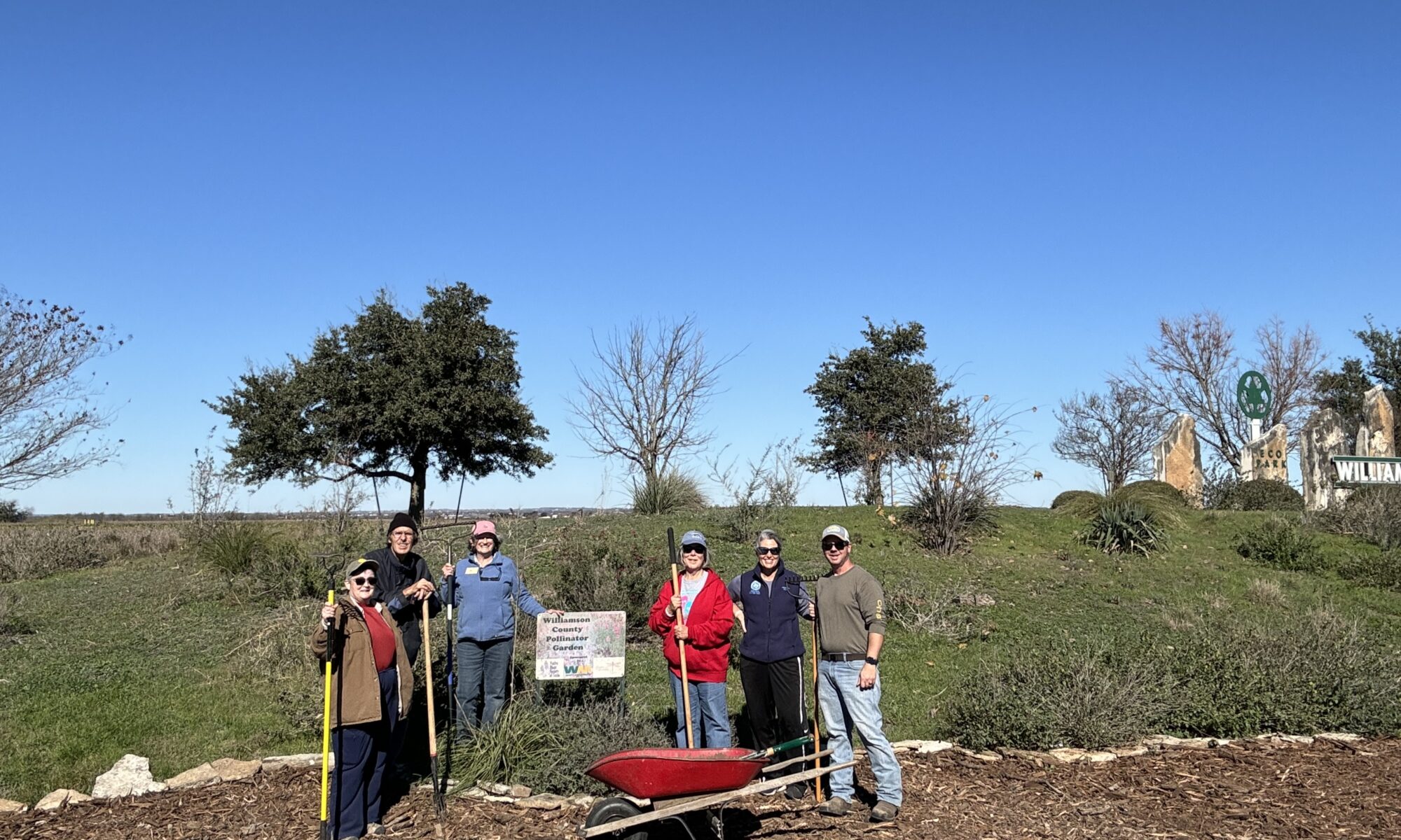 This image shows the volunteer crew gathered around the project sign in celebration of completing the mulch spreading.